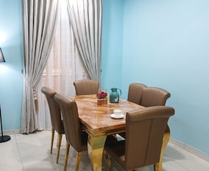 Uma área de refeições com uma mesa de madeira e quatro cadeiras, um jarro, uma xícara e um cesto com flores.