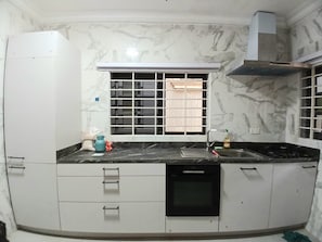 A kitchen with a built-in oven, a window with blinds, and a stove. - 2-bedroom apartment in serene Greater Accra Region with AC (Greater Accra Region)