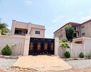 A gated entrance to a residential building with a flat roof and a balcony. - 2-bedroom apartment in serene Greater Accra Region with AC (Greater Accra Region)
