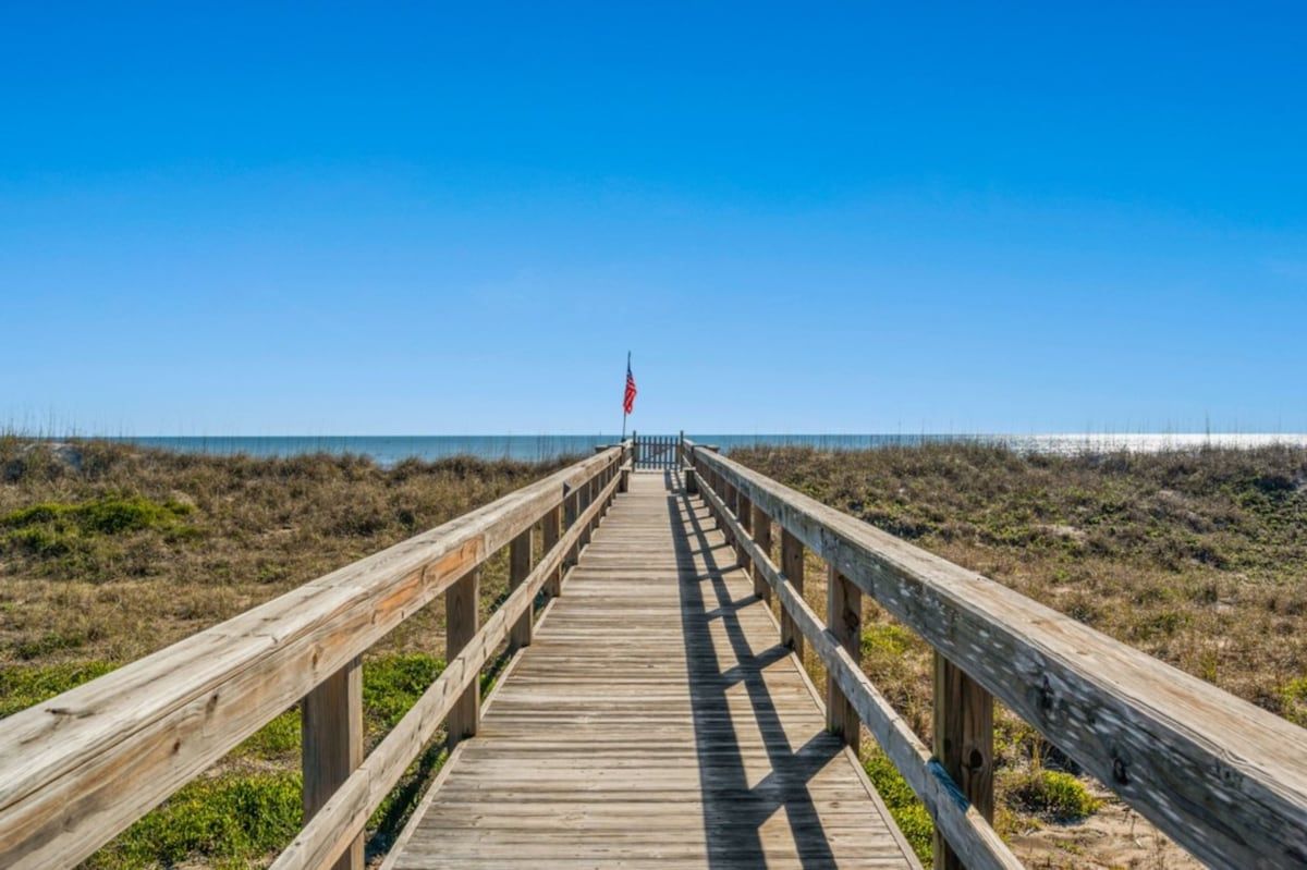 Een houten vogelzangpad dat naar een strand leidt, met een Amerikaanse vlag.