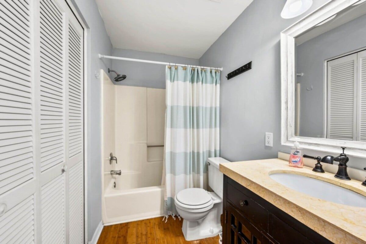 A bathroom with a bathtub, toilet, and vanity with a mirror.