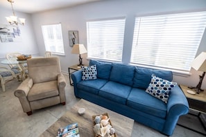 Ein Wohnzimmer mit einem blauen Sofa, einem beigen Sessel und einem Couchtisch mit Dekoration.