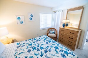 Ein Schlafzimmer mit Bett, Schminktisch, Sessel und Wandbildern.