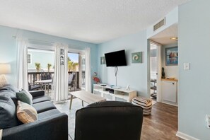 Ein Wohnzimmer mit einer Couch, einem Fernseher und einem Essbereich mit Tisch und Stühlen.