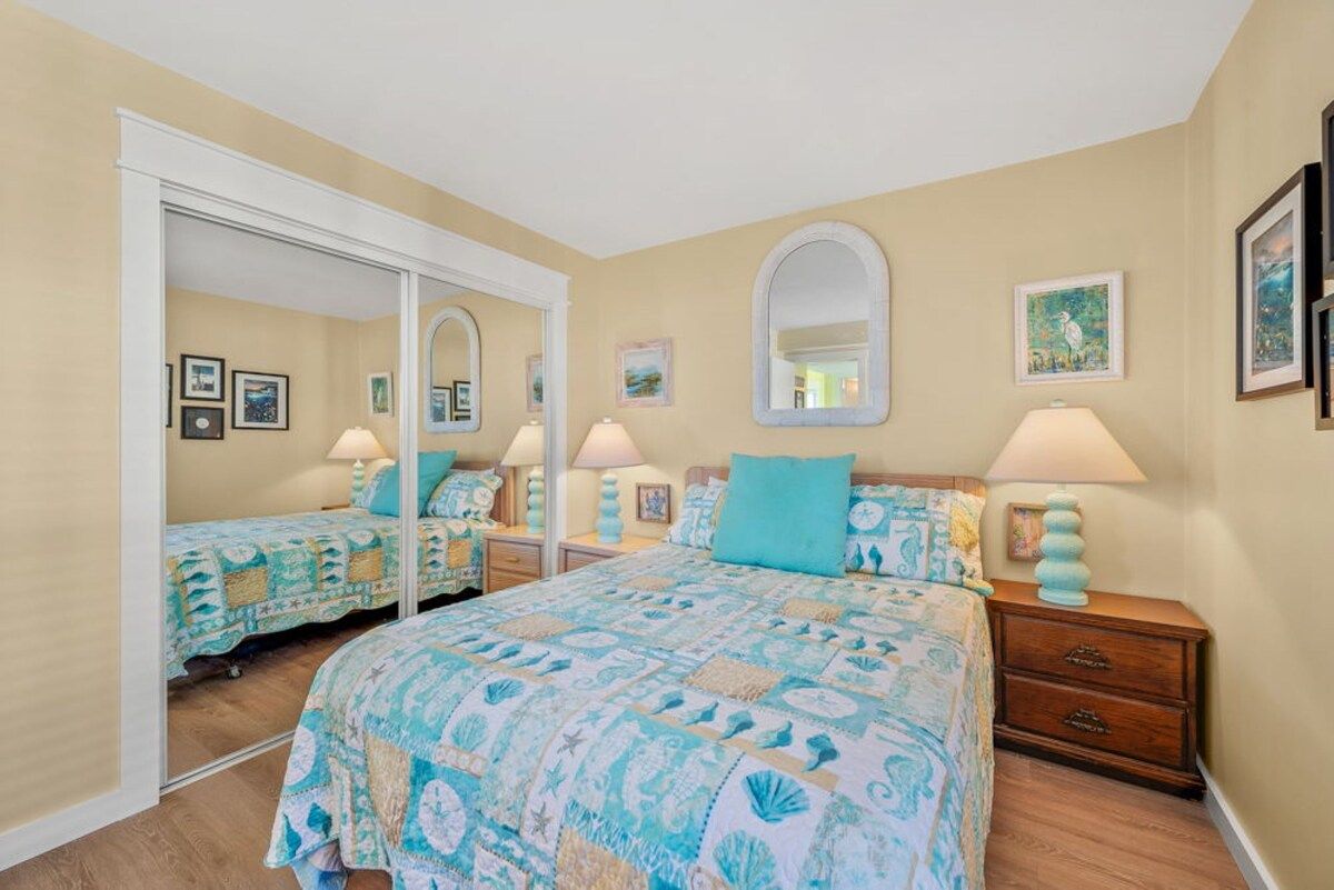 Une chambre à coucher avec un grand lit, deux tables de chevet, un miroir et une armoire.