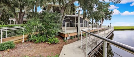 A waterfront property with a wooden deck, metal railing, and a building with a covered area.
