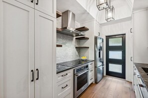 A modern kitchen with white cabinetry, a stainless steel range hood, a built-in oven, and a refrigerator. - Omni Amelia Island 2BR Lagoon Villa | Walk to Beach | Sleeps 4 (Fernandina Beach)
