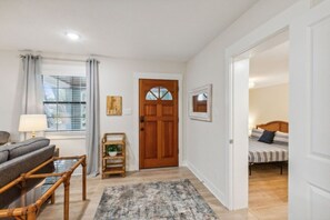 Habitació amb llit, sofà, porta de fusta i finestra amb cortines.