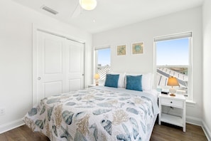 A bedroom with a bed, two bedside tables, a window with a view, and a door. - Ocean View Beach House on Amelia Island with Private Elevator and Pool (Fernandina Beach)