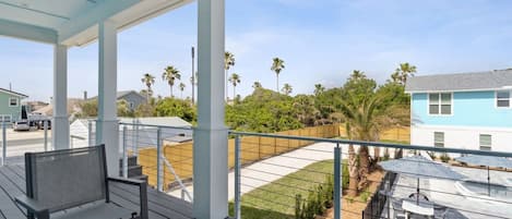 Un espace extérieur abrité, aménagé avec des sièges, offrant une vue sur un quartier résidentiel et un ciel dégagé.