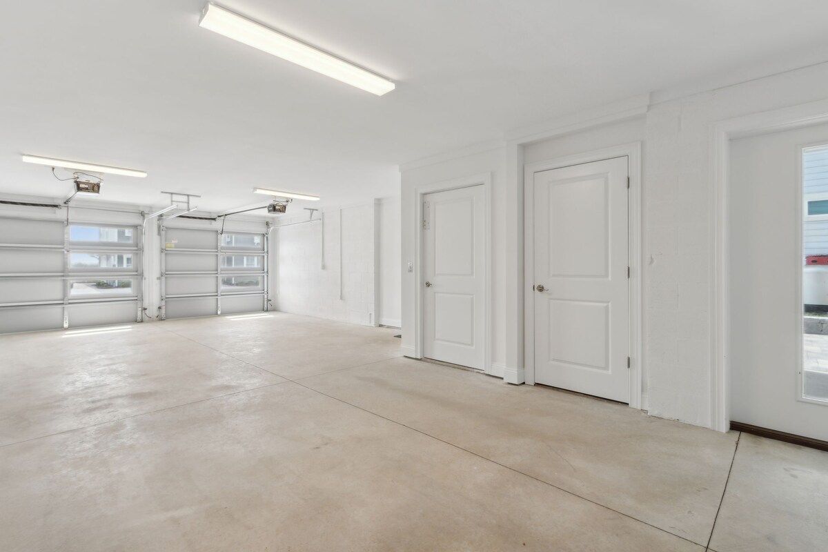A spacious garage with white walls, a concrete floor, and three garage doors.
