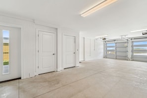 A clean, spacious garage with white doors and a concrete floor. - Brand New 4BR • Ocean Views • Pool (Fernandina Beach)