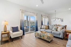 A living room with a sofa, armchair, ottoman, and a lamp. - Brand New 4BR • Ocean Views • Pool (Fernandina Beach)