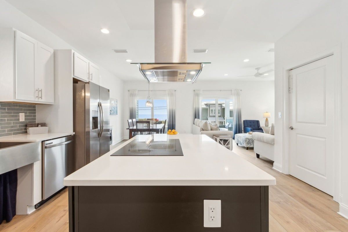A modern kitchen with a central island, stainless steel appliances, and a view to the living area.