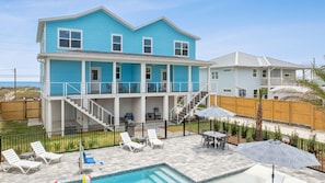 Ein zweistöckiges Haus mit Pool, Sitzgelegenheiten im Freien und einer überdachten Terrasse.