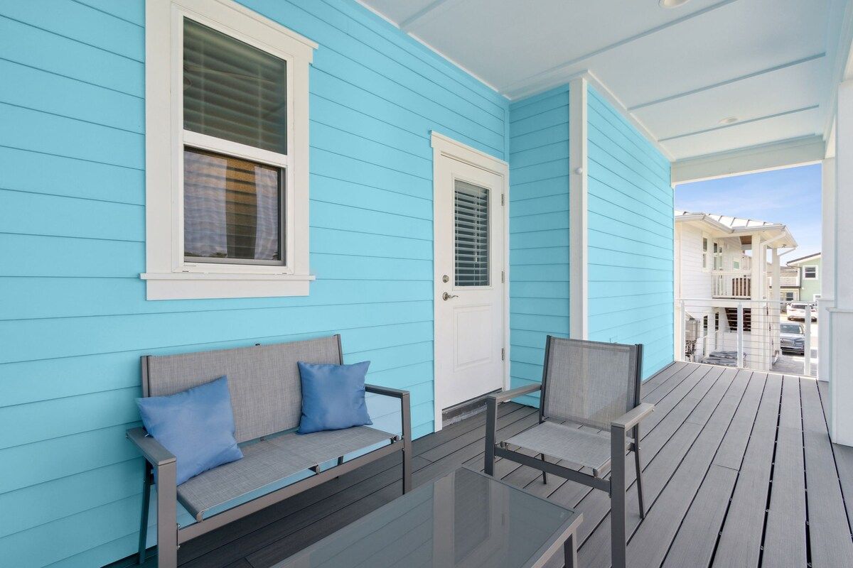 A porch with a blue exterior, a white door, and a glass table.
