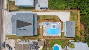 Eine Vogelperspektive auf ein Wohnanwesen mit Swimmingpool, einem großen dreieckigen Gebäude und einem kleineren, rechteckigen Gebäude.