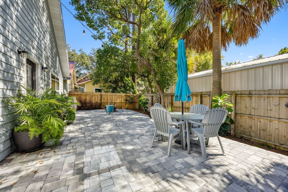A patio with a table and chairs, surrounded by a wooden fence and potted plants.