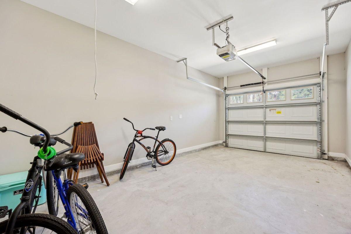 A garage with two bicycles, a wooden chair, and a metal garage door.