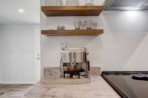 Eine Küche mit einer integrierten Espressomaschine, Holzregalen und einer Arbeitsplatte.
