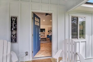 A house entrance with a blue door, a welcome sign, and a ceiling fan. - 4BR Retreat • Fire Pit • 1 Mile to Beach (Fernandina Beach)