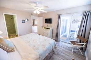 Ein Schlafzimmer mit einem Bett, einem Deckenventilator, einem Fernseher, einem Schreibtisch und einem Stuhl.