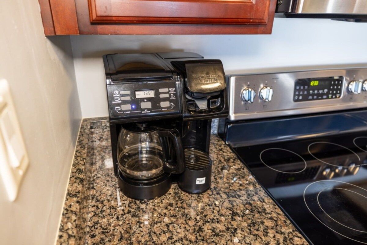 Eine Kaffeemaschine mit digitaler Anzeige und einer Kaffeekanne auf einer Granit-Arbeitsplatte.