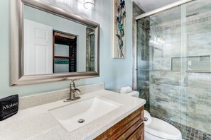 Een badkamer met een grote spiegel, een wastafel, een toilet en een douchecabine.