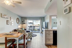 A cozy living area with a dining table, chairs, a sofa, and a view of the outdoors through a sliding door. - Waterfront Amelia Island Condo with Ocean View, Elevator Access, and Pool (Fernandina Beach)