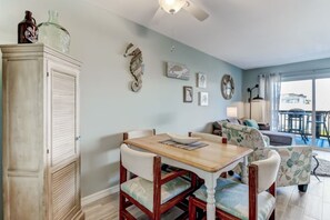 A dining area with a wooden table and chairs, a cabinet, and wall art. - Waterfront Amelia Island Condo with Ocean View, Elevator Access, and Pool (Fernandina Beach)