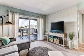 Een woonkamer met een bank, televisie en een schuifdeur naar een terras.