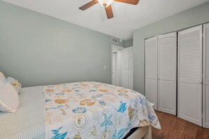 A bedroom with a bed, a ceiling fan, and a set of white closets. - 3BR Condo • Pool • Walk to Beach • Sleeps 6 (Fernandina Beach)