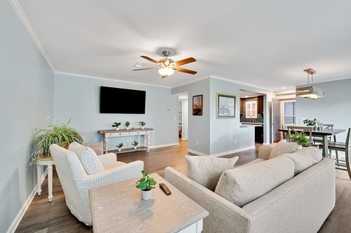 A living room with a sofa, a coffee table, a television, and a ceiling fan.