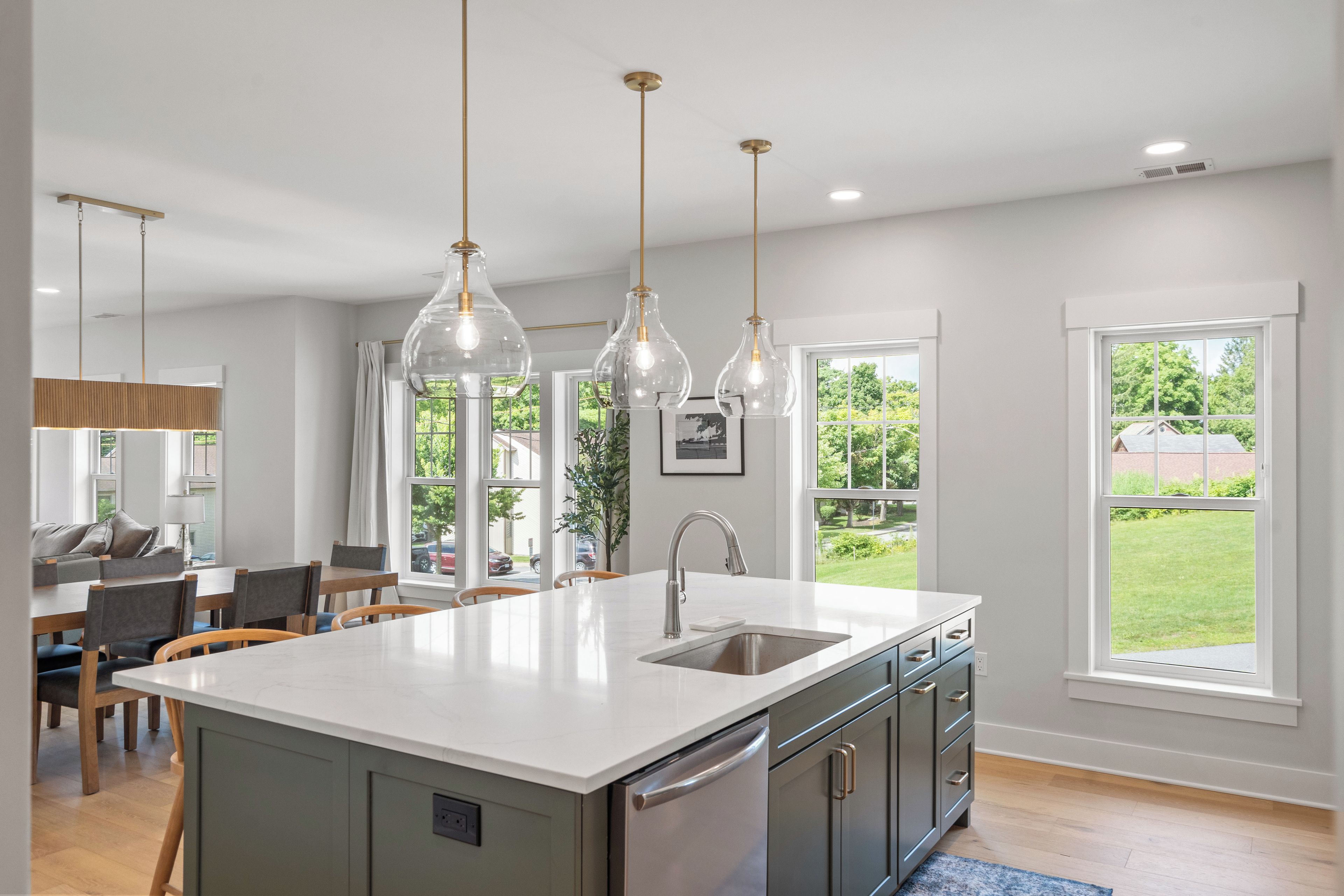 A modern kitchen with a central island, pendant lighting, and a view of the outdoors.