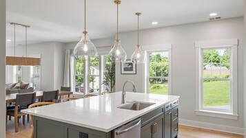 A modern kitchen with a central island, pendant lighting, and a view of the outdoors.