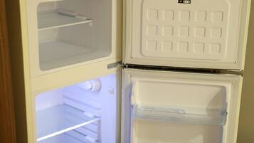 Uma geladeira branca com duas portas, compartimento de freezer e uma prateleira.