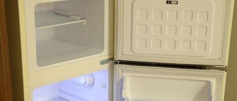 A white refrigerator with two doors, a freezer compartment, and a shelf.