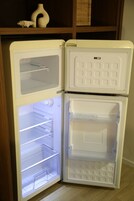 Un refrigerador blanco con dos puertas, un compartimento congelador y un estante.