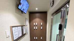 A hallway with a mounted television, a bulletin board with notices, a white speaker, and a door with a glass panel. - Stay on you Gwangmyeong Station (Gwangmyeong)