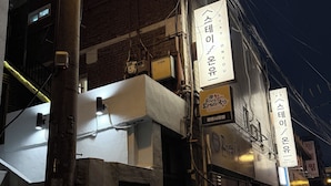 A building with multiple signs, including one with Korean text and another with a phone number. There are visible electrical wires and a brick wall. - Stay on you Gwangmyeong Station (Gwangmyeong)
