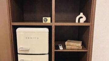 A wooden cabinet with a white appliance, shelves with books, a bowl, and a folded towel.