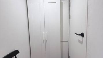 A narrow hallway with a black chair, a blue rug, and white double doors.