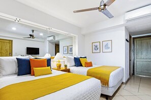 Una camera d'albergo con due letti, una ventola a soffitto, una televisione a schermo piatto e una porta.