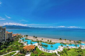 A resort with multiple swimming pools, a beach, and a view of the ocean and mountains. - Beachfront-2 BR Plus 2 BR-Apartment Shared Balcony (Puerto Vallarta)