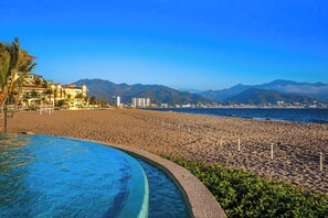 Una località balneare con piscina, vista sulla spiaggia e montagne sullo sfondo.