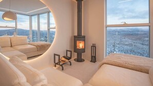 Een modern interieur met een open haard, een bank en een groot raam met uitzicht.