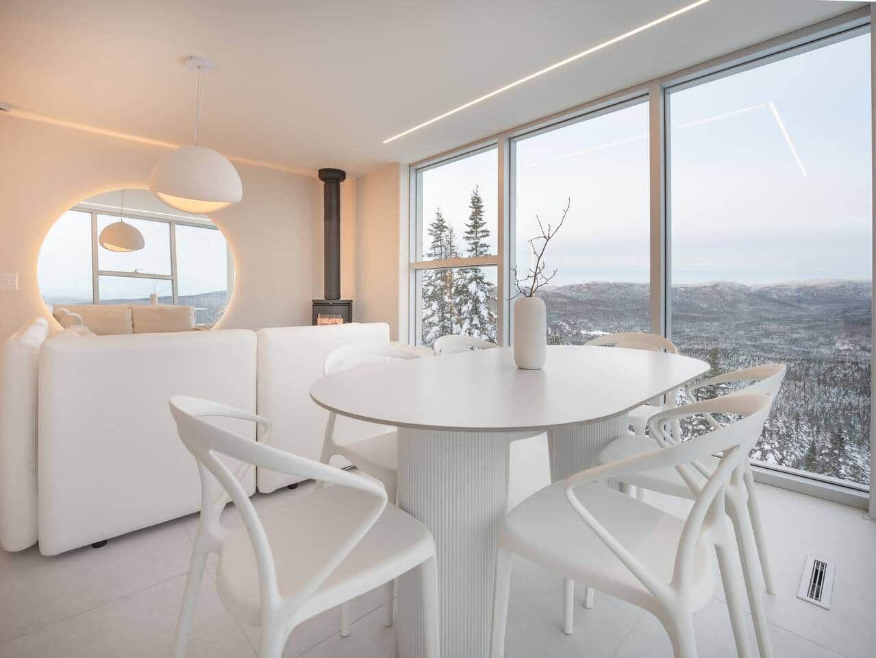 A modern interior with a round dining table, white chairs, and a sofa.