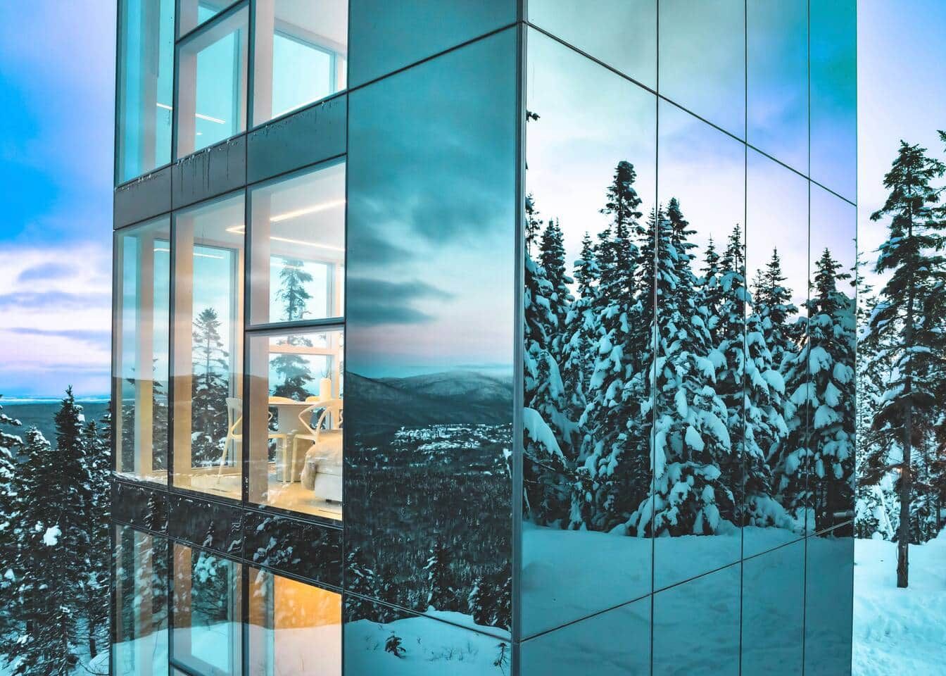 A modern building with large glass windows reflecting a snowy landscape.