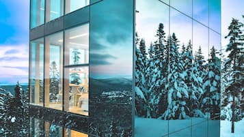 A modern building with large glass windows reflecting a snowy landscape.