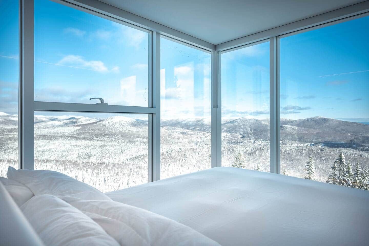 A bedroom with a large window offering a view of a snowy landscape.